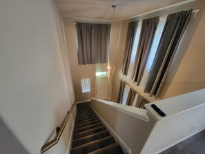 A staircase with a handrail, a window with blinds, and a door at the top. - Spacious 4-bedroom house in charming Richmond with AC (Richmond)