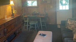 Ein Holzinterieur mit einem Esstisch, Stühlen, einer Couch, einer Lampe und einem Deckenventilator.