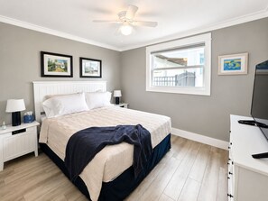 A bedroom with a bed, nightstands, a ceiling fan, a window with a view, and framed pictures on the wall. - Waterfront Retreat - Dock, Bay Front, Beach Access (Englewood)