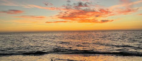 Ein Strand mit Wellen und einem Sonnenuntergang.