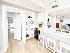 A modern kitchen with white cabinetry, a central island with stools, and a view into the dining area. - Waterfront Retreat - Dock, Bay Front, Beach Access (Englewood)
