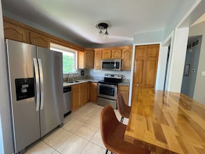 A kitchen with stainless steel appliances, wooden cabinets, a microwave, and a dishwasher.