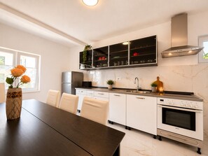 Eine moderne Küche mit weißen Schränken, einem Bosch-Ofen, einer eingebauten Mikrowelle und einem Fenster mit Blick.