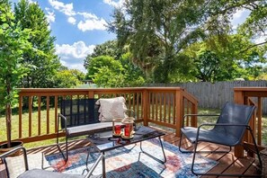 A wooden deck with a table, two chairs, and a bench. - 15 mins to TPA, Fire pit & Pullout Couch (Tampa)