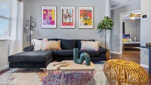 Una sala de estar moderna con un sofá negro, una mesa de centro y tres obras de arte enmarcadas en la pared.