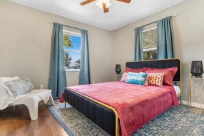 A bedroom with a bed, a chair, a nightstand, and a window with curtains. - 15 mins to TPA, Fire pit & Pullout Couch (Tampa)