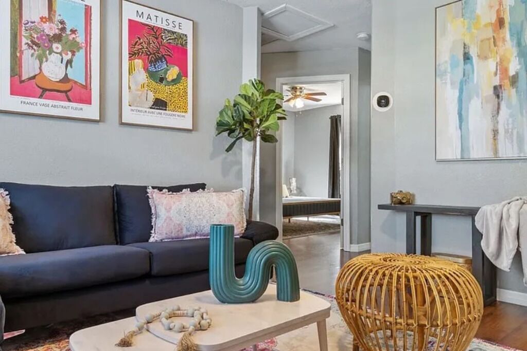 A living room with a sofa, a coffee table, a decorative vase, and a wicker ottoman.
