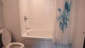 Une salle de bain équipée de toilettes, d’une baignoire et d’un rideau de douche.