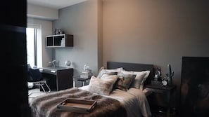 Ein Schlafzimmer mit Bett, Schreibtisch, Stuhl und Nachttischen.