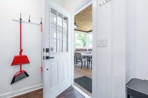 A white door with a red broom hanging on the wall, a window, and a view of an outdoor deck with chairs. - The Northview Nook: Fenced Yard, Dog-Friendly, & East Nashville, Near Broadway (Nashville)