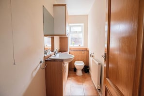 A small bathroom with a sink, mirror, toilet, and window. - Large Contractor Accommodation Near Universal | Sleeps 10 | Long Stay Discount (Bedford)