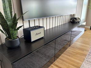 A modern living room with a flat-screen TV, a Marshall speaker, and a potted plant. - Dockside Retreat- Riverfront Near Lake Michigan (St. Joseph)