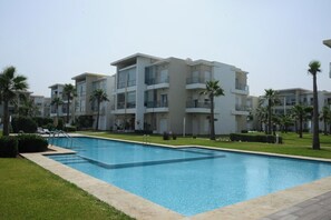 Un hôtel moderne doté d’une piscine, de nombreux balcons et de palmiers.
