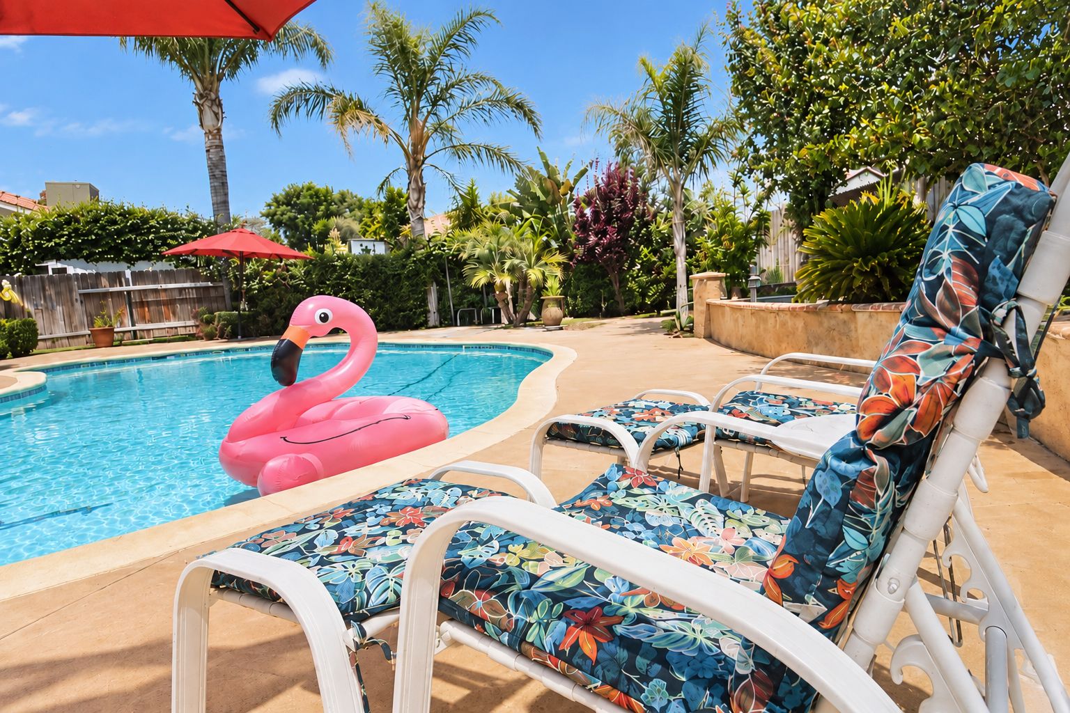 Een zwembad met ligbedden en een roze flamingo drijver.