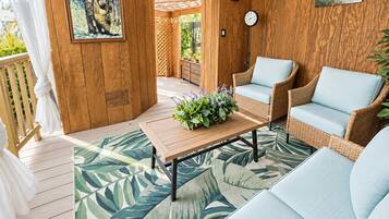 A wooden deck with wicker furniture, a clock, and a plant.