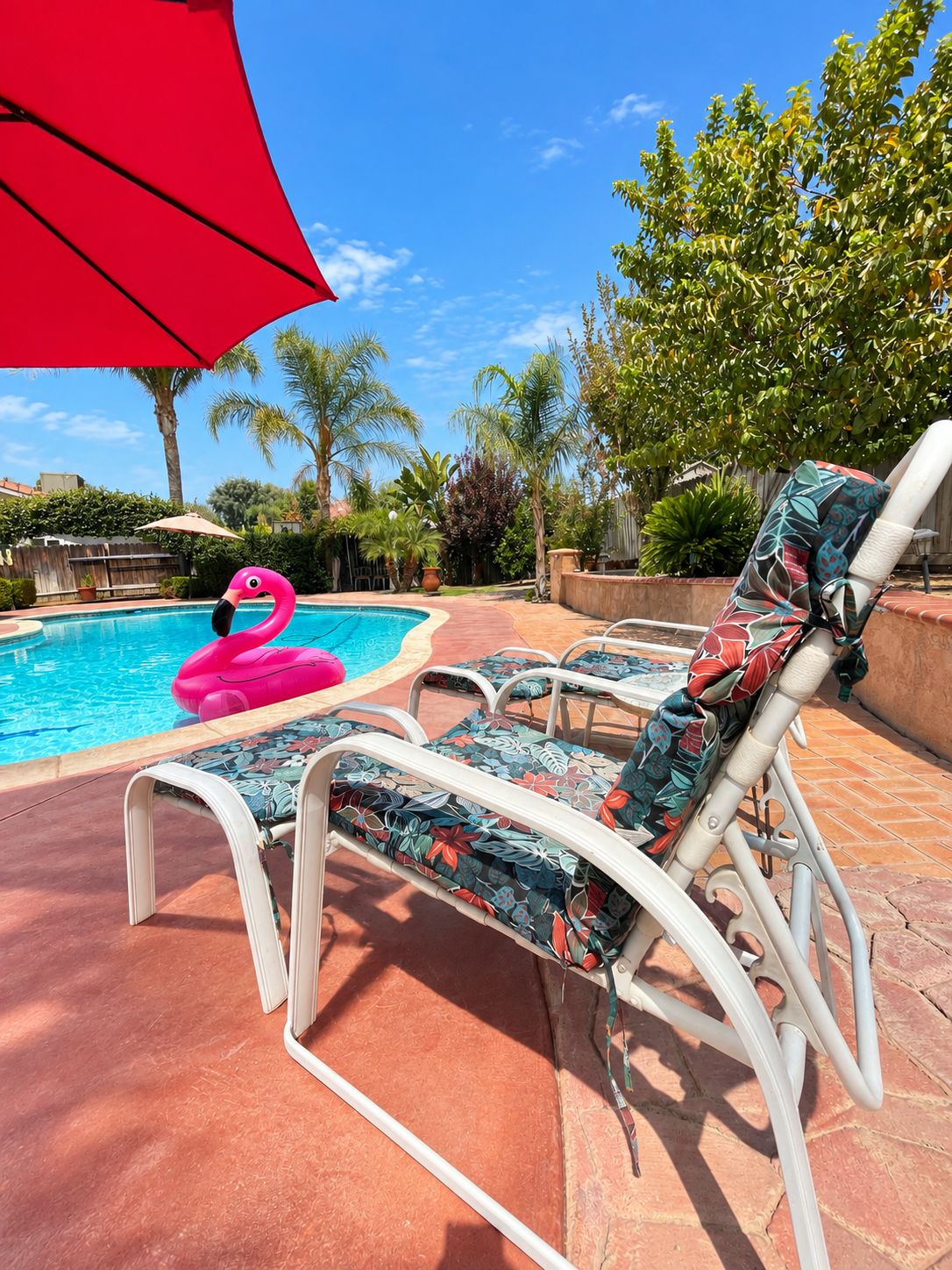 A swimming pool with lounge chairs and a pink flamingo float.