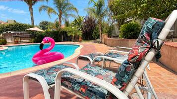 A swimming pool with lounge chairs and a pink flamingo float.