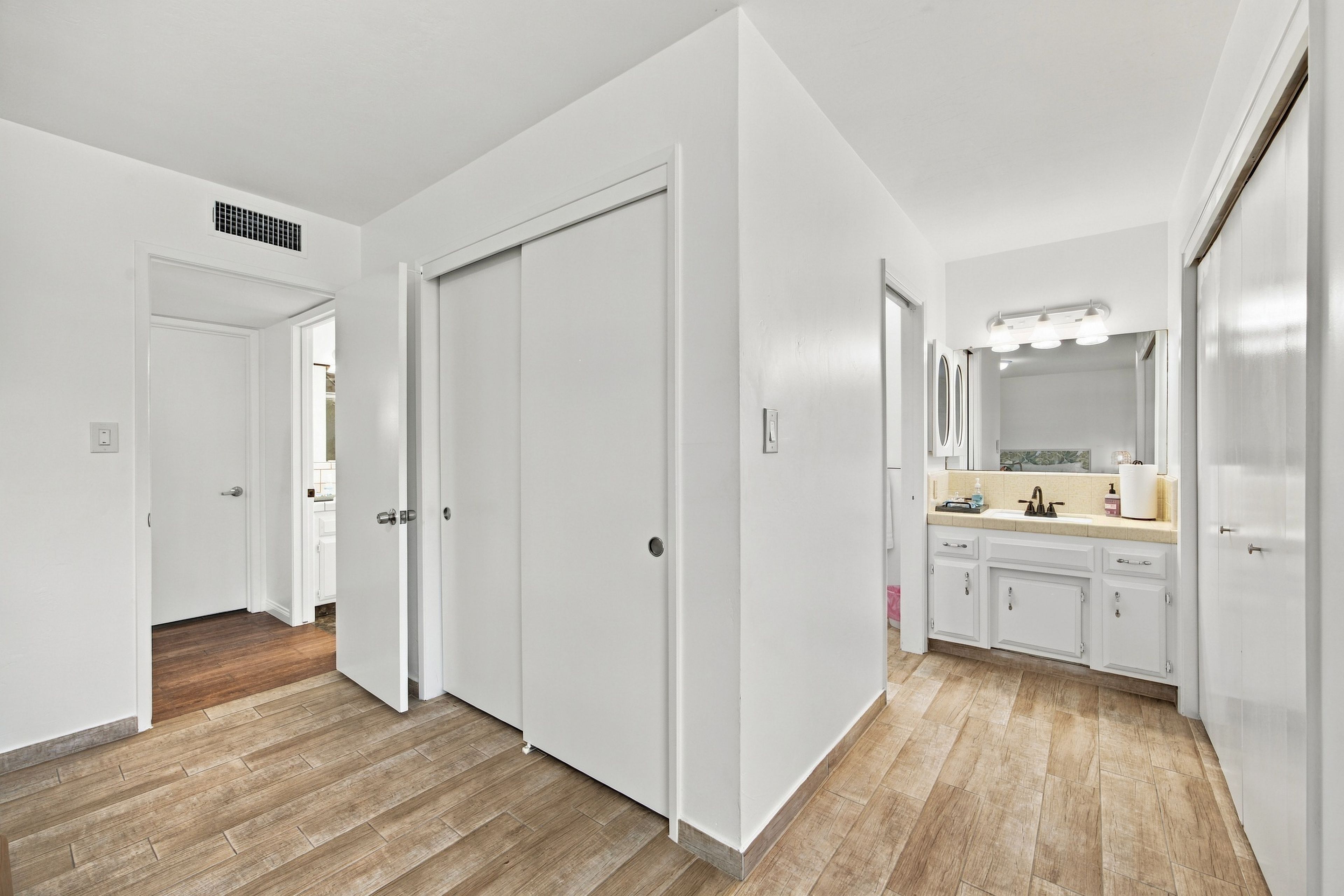 A modern bathroom with a large mirror, sink, and cabinets.