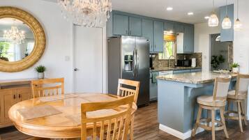 A modern kitchen with a central island, stainless steel appliances, and a chandelier.