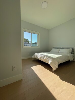 Un dormitorio con cama, ventana y lámpara en el techo.