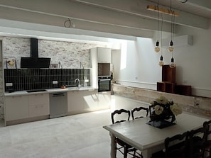 A modern kitchen with a brick wall backsplash, a built-in oven, and a dining area with a table and chairs.