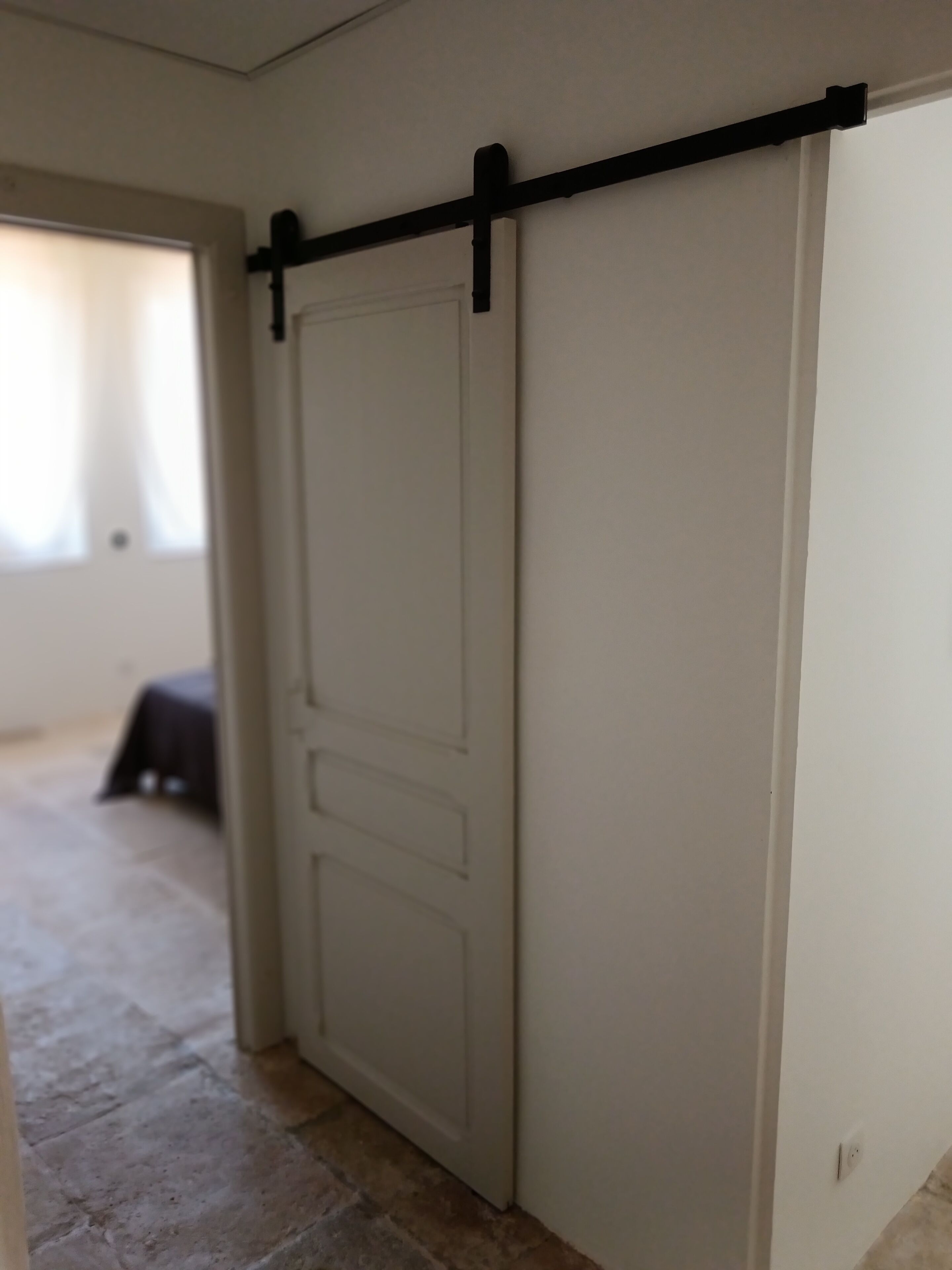 A hallway with a sliding door, a black horizontal bar, and a small table in the background.