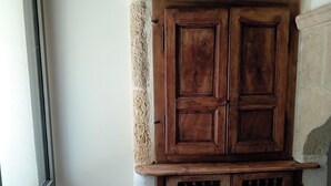 A corner with a wooden cabinet, a window, and a wooden stool with flowers. - Mas in the middle of vineyards, ideally located between Camargue and Provence. (Vauvert)