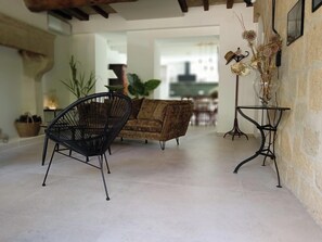 Una sala de estar con un sofá, una silla negra y una mesita con un jarrón.