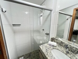 A bathroom with a glass shower enclosure, a granite countertop, a sink, and a mirror. - LK Santa Efigênia 3 (Belo Horizonte)