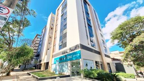 Un bâtiment moderne avec une devanture portant l’inscription « AUDIO+ AUDITIVOS » et un ciel dégagé.