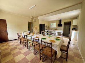 A dining area with a checkered floor, wooden chairs, a table set with plates, glasses, and a vase with dried plants. - Vacation Home in the Alpilles, Provence (Noves)