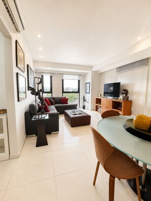 Een moderne woonkamer met een bank, salontafel, televisie en een eethoek.