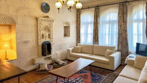 Ein Wohnzimmer mit einer Couch, einem Couchtisch, einem gemusterten Teppich, einem Kamin und einer Chandelier.