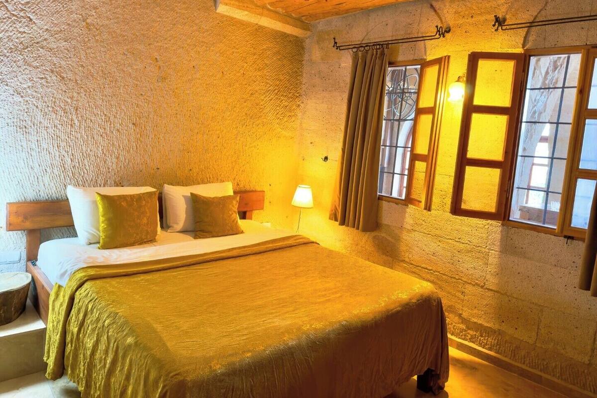 A cozy room with a bed, wooden headboard, and a window with curtains.