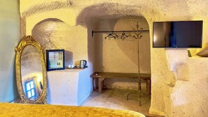 Ein Zimmer mit einem großen Spiegel, einem Flachbildfernseher, einer Bank und einem Kleiderständer.