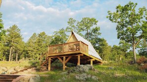 Une cabane en bois dotée d’un balcon, entourée d’arbres et de rochers.