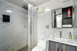 Een badkamer met een douche, toilet, wastafel en spiegel.