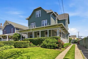 A two-story house with a porch, a well-maintained lawn, and a clear sky.