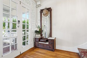 A room with a wooden dresser, a large mirror, and a white door with multiple windows.