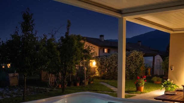 Ein Whirlpool in einer Außenanlage mit einer Holzterrasse, umgeben von Topfpflanzen und einem Sternenhimmel.