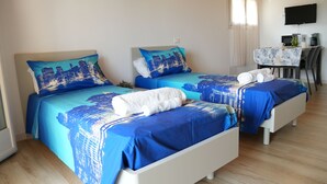 Ein Hotelzimmer mit zwei Betten, einem Schreibtisch und einem Fernseher.