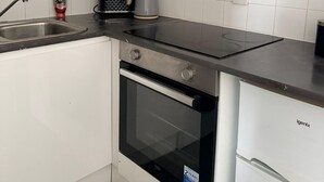 Ett kök med vita skåp, en fläktkåpa i rostfritt stål, en vattenkokare och en diskmaskin.