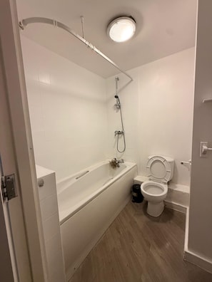 A bathroom with a bathtub, a shower, and a toilet. - Apart Studio (Manchester)