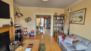A living room with a fireplace, a sofa, a bookshelf, and a dining area. - Attractive 3-bedroom house in scenic Oranmore for your getaway (Oranmore)
