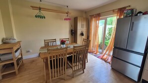 A dining area with a wooden table and chairs, a refrigerator, and a window with curtains. - Attractive 3-bedroom house in scenic Oranmore for your getaway (Oranmore)