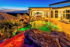 Une piscine avec un toboggan, des chaises longues et un espace patio.