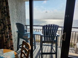 Un balcon avec deux fauteuils Adirondack, une table et une vue sur l’océan.
