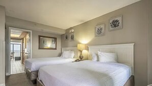 Ett hotellrum med två sängar, en sittgrupp och utsikt över balkongen.
