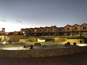 Ein Innenhof mit einem Brunnen, Steinmauern und einer Reihe von Gebäuden mit einheitlicher Architektur.
