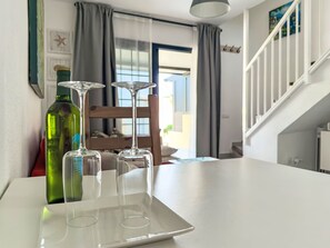 Ein Essbereich mit einem Tisch, drei Weingläsern und einer grünen Flasche.